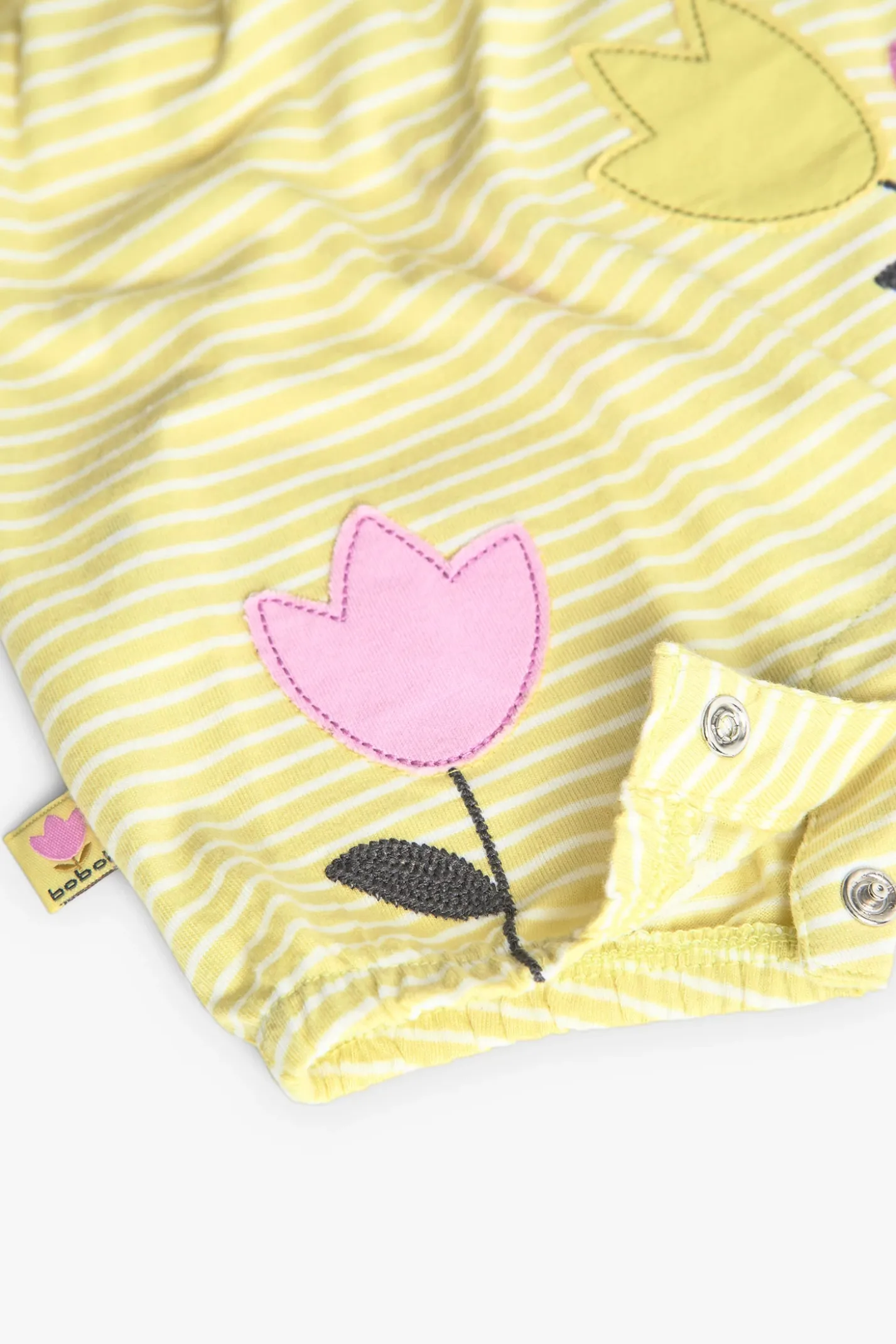 Pagliaccetto in maglia per bambina in colore giallo a righe con motivo floreale.