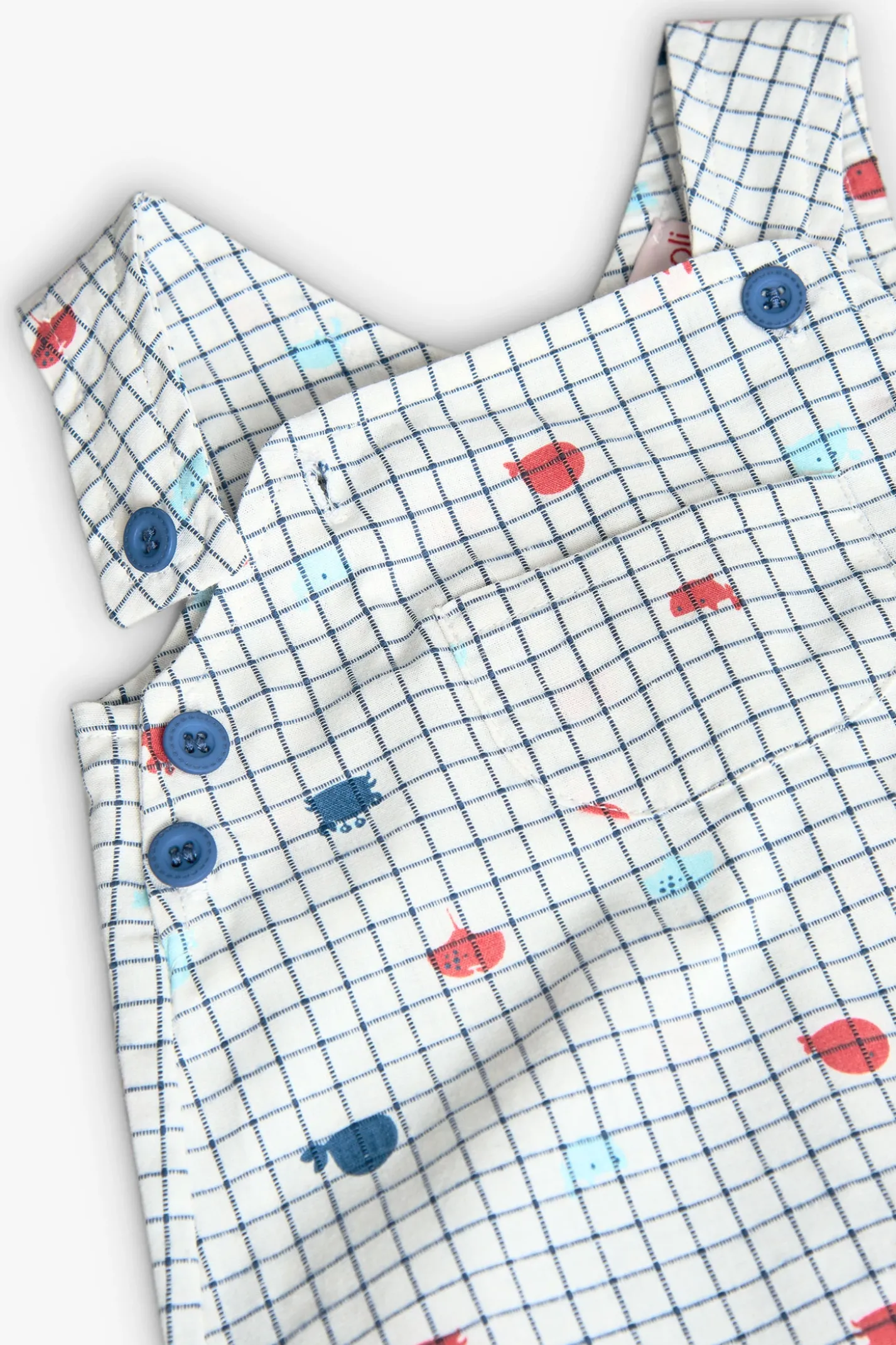 Salopette in popeline per bambino in colore bianco con stampa a quadri in blu e rosso.