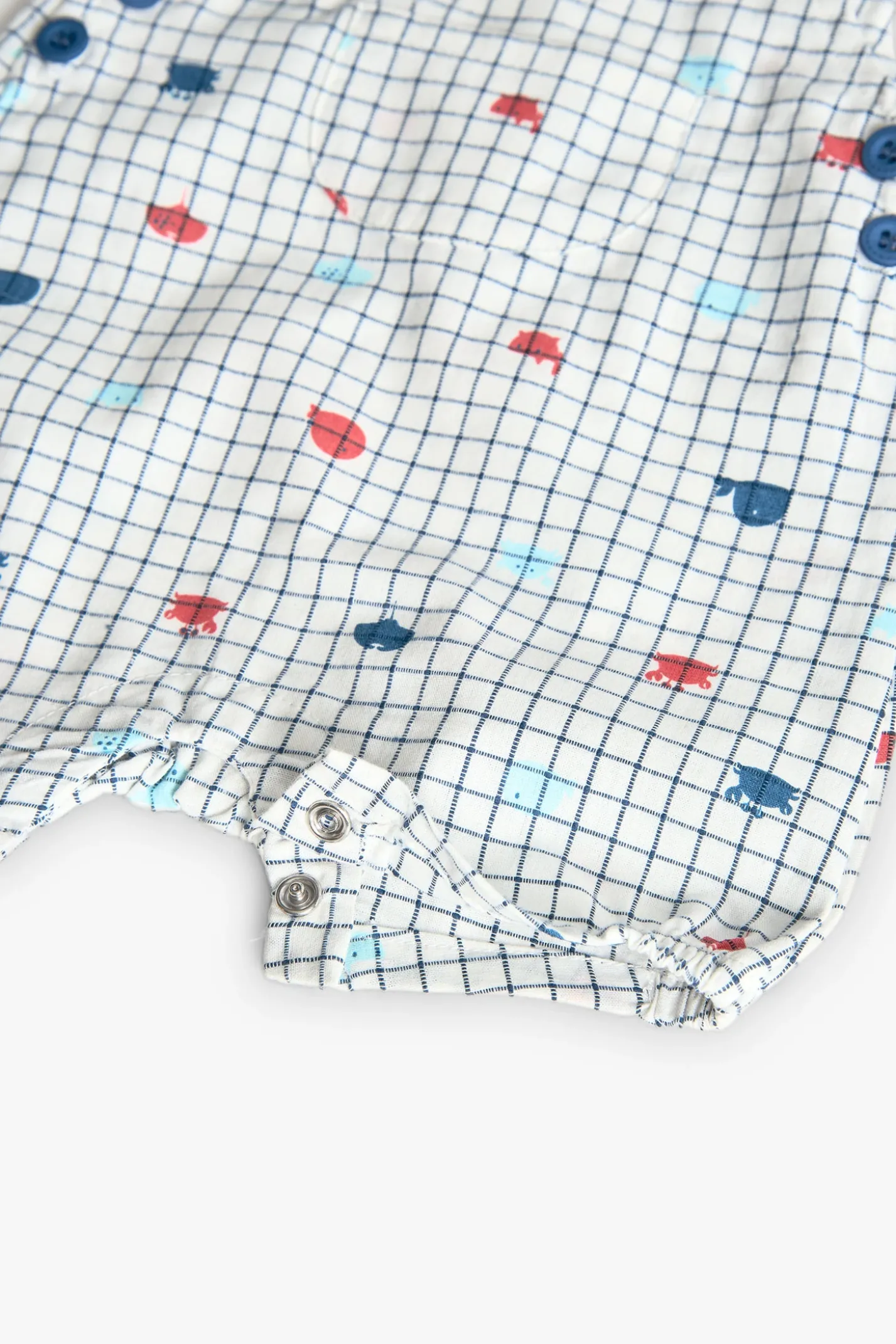 Salopette in popeline per bambino in colore bianco con stampa a quadri in blu e rosso.